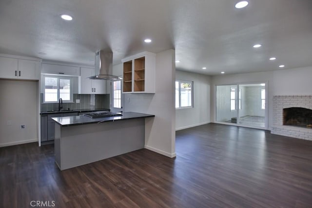 kitchen featuring kitchen peninsula, dark hardwood / wood-style flooring, wall chimney exhaust hood, sink, and white cabinetry