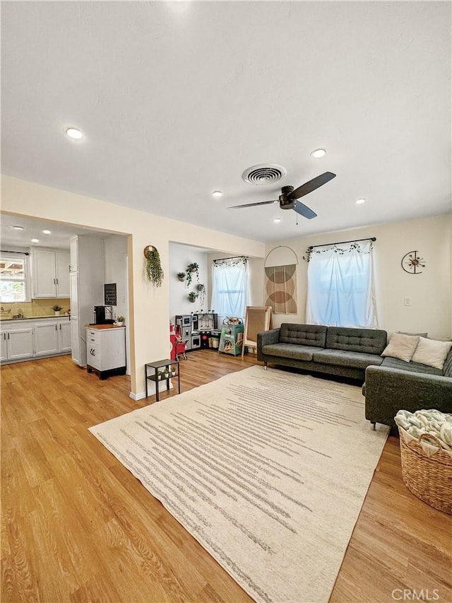 living room with plenty of natural light, ceiling fan, and light hardwood / wood-style flooring