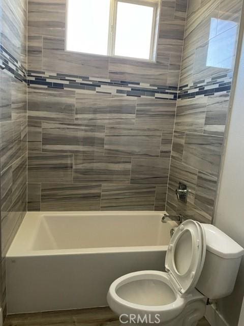 bathroom with tiled shower / bath combo and toilet