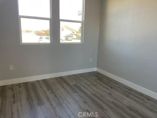 empty room with dark hardwood / wood-style flooring and plenty of natural light