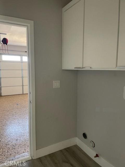 laundry area featuring hardwood / wood-style floors and cabinets