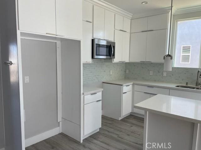 kitchen with white cabinets, light hardwood / wood-style floors, sink, and tasteful backsplash