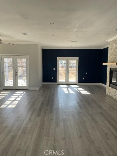 unfurnished living room with crown molding, french doors, plenty of natural light, and hardwood / wood-style flooring