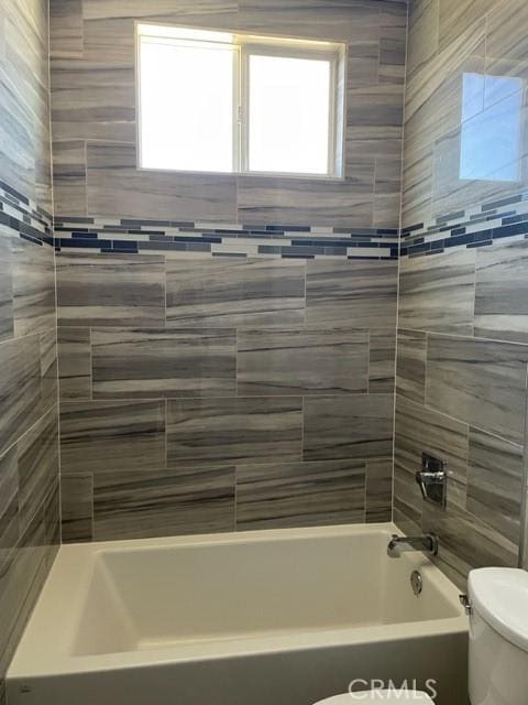 bathroom featuring toilet and tiled shower / bath