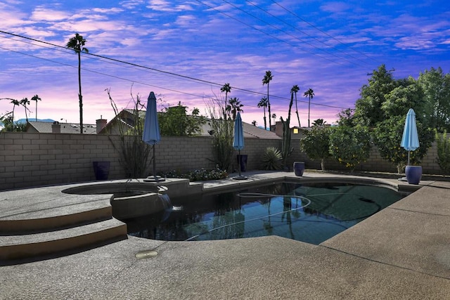 pool at dusk with an in ground hot tub