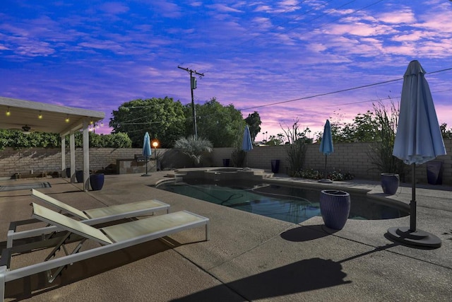 pool at dusk with a patio area