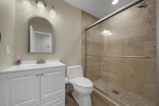 bathroom featuring tile patterned flooring, a shower with door, vanity, and toilet