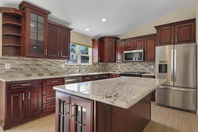 kitchen with decorative backsplash, light stone counters, stainless steel appliances, a center island, and lofted ceiling