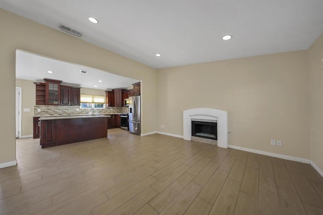 kitchen featuring stainless steel refrigerator with ice dispenser, a center island, light hardwood / wood-style flooring, and backsplash