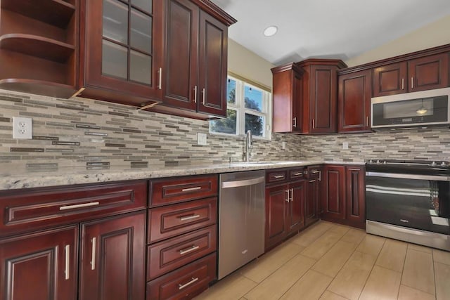 kitchen with light stone countertops, appliances with stainless steel finishes, backsplash, and sink