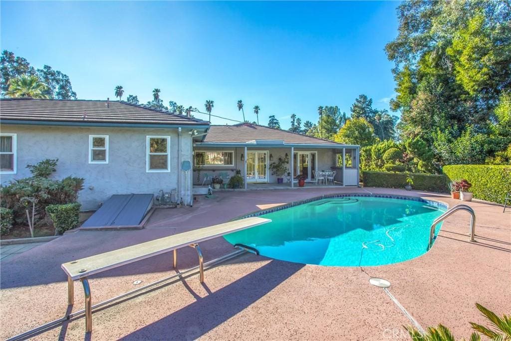 view of swimming pool with a patio and a diving board