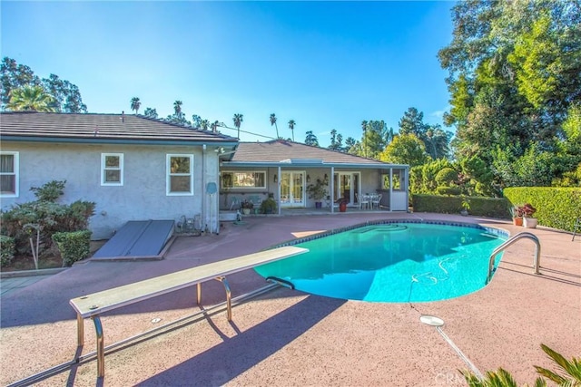 view of swimming pool with a patio and a diving board