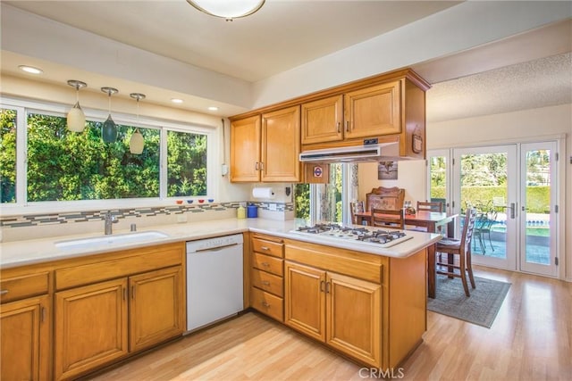 kitchen with kitchen peninsula, white appliances, sink, and a wealth of natural light