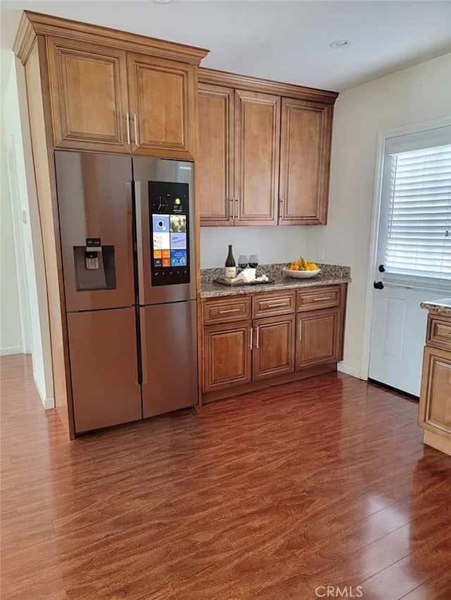 kitchen featuring stone counters, stainless steel fridge with ice dispenser, and dark hardwood / wood-style flooring