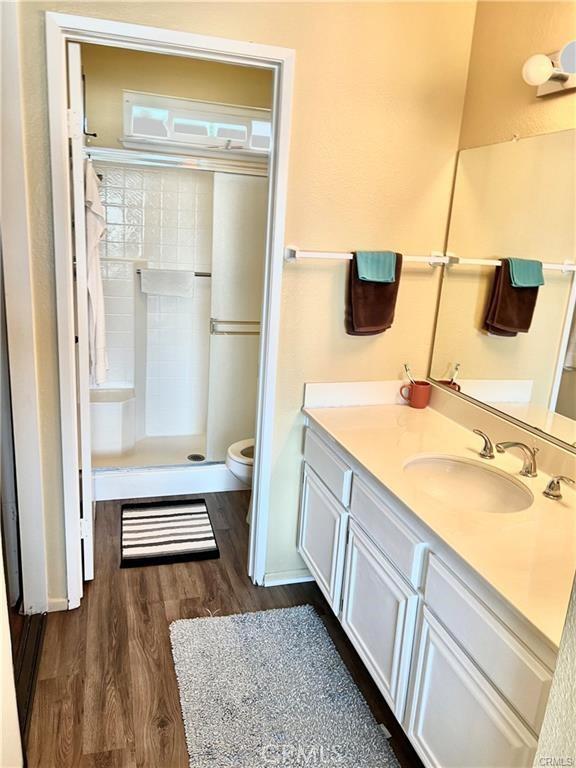 bathroom featuring hardwood / wood-style floors, vanity, toilet, and a shower