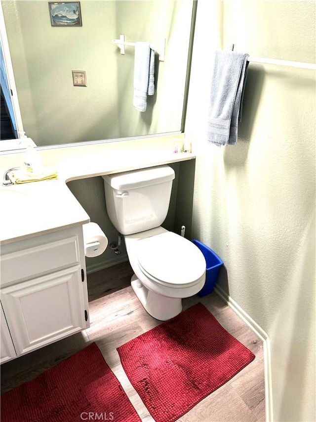 bathroom with hardwood / wood-style floors, vanity, and toilet