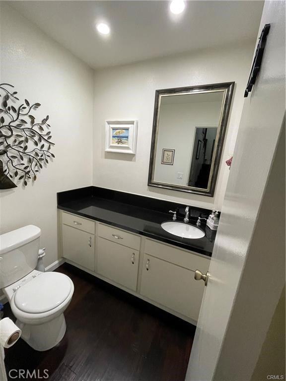 bathroom with hardwood / wood-style floors, vanity, and toilet