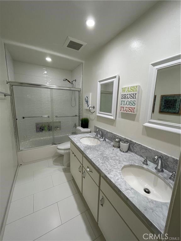 full bathroom featuring tile patterned flooring, vanity, bath / shower combo with glass door, and toilet