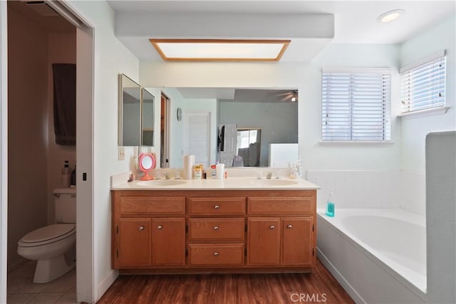 bathroom with a tub to relax in, hardwood / wood-style flooring, vanity, and toilet