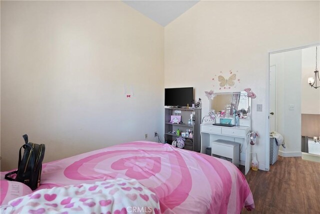 bedroom with dark hardwood / wood-style flooring, high vaulted ceiling, and a notable chandelier