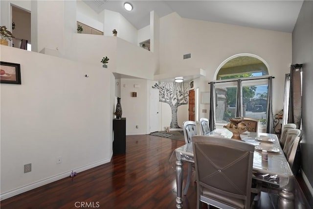 dining space featuring dark wood-type flooring and high vaulted ceiling