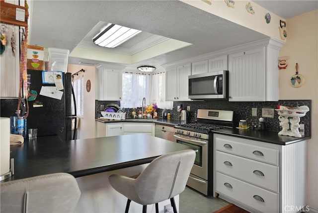 kitchen with sink, stainless steel appliances, backsplash, white cabinets, and ornamental molding