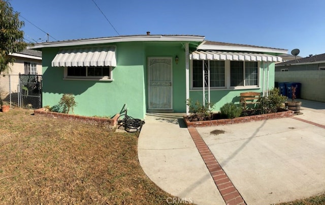 bungalow featuring fence, a patio, and stucco siding