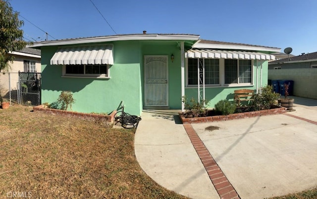 bungalow with a gate, fence, and stucco siding