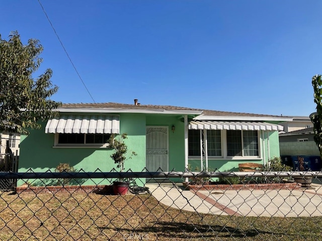 view of front of home with a fenced front yard, a front yard, and stucco siding