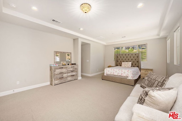 bedroom with a raised ceiling and light carpet