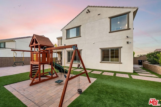 playground at dusk featuring a patio area and a yard