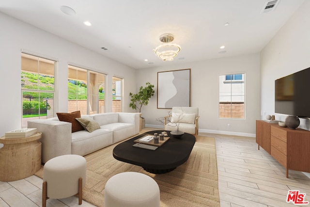 living room with a chandelier, light wood-type flooring, and a healthy amount of sunlight