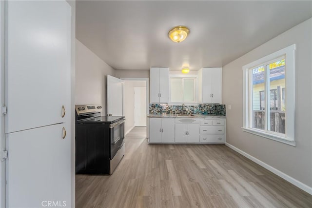 kitchen featuring tasteful backsplash, stainless steel electric stove, sink, white cabinets, and light hardwood / wood-style floors