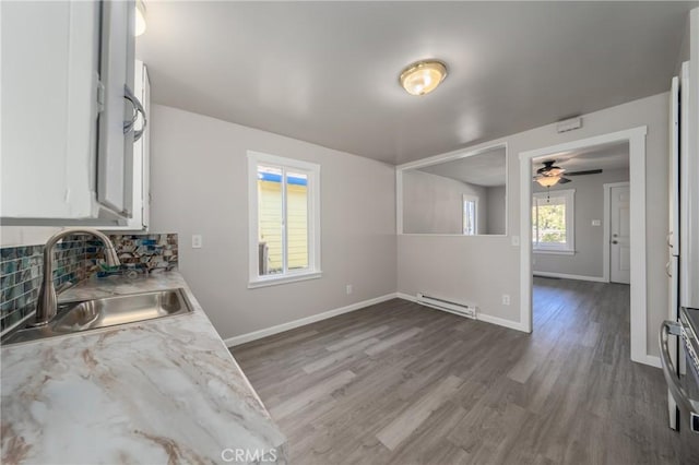 kitchen featuring backsplash, sink, a baseboard radiator, white cabinets, and hardwood / wood-style floors