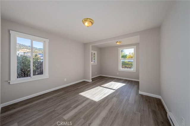 unfurnished room featuring dark hardwood / wood-style floors, a wealth of natural light, and a baseboard radiator