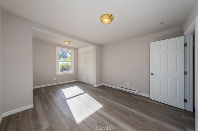 unfurnished bedroom featuring a closet, dark hardwood / wood-style flooring, and a baseboard heating unit