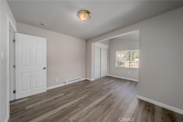 spare room with hardwood / wood-style flooring and a baseboard heating unit