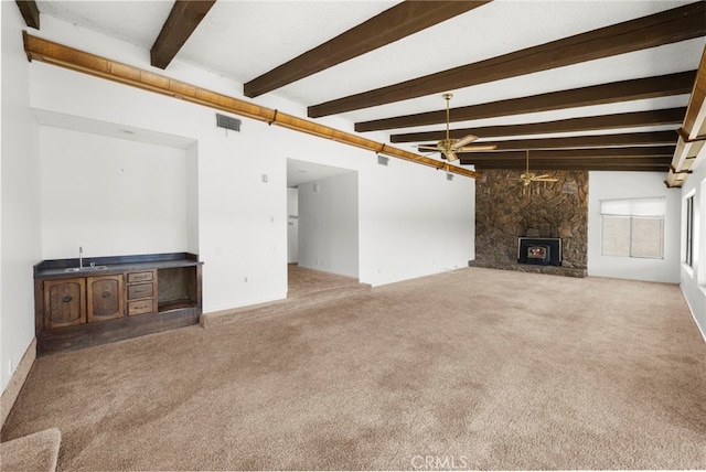 unfurnished living room featuring carpet floors, a fireplace, visible vents, a sink, and ceiling fan