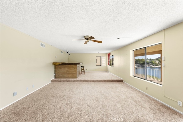 unfurnished living room with visible vents, carpet flooring, and a textured ceiling