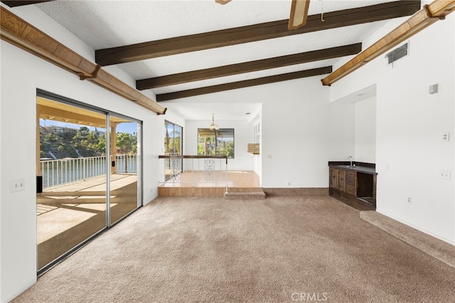 unfurnished living room featuring beam ceiling, visible vents, carpet flooring, a sink, and a textured ceiling