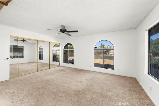 interior space with a ceiling fan, carpet flooring, and a textured ceiling