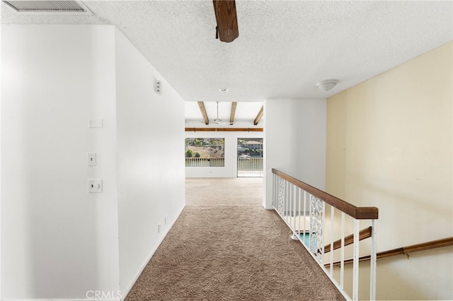 hallway with baseboards, carpet, visible vents, and a textured ceiling