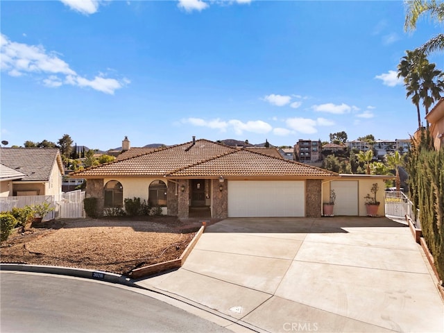 view of front of home with a garage, concrete driveway, a tile roof, fence, and stucco siding