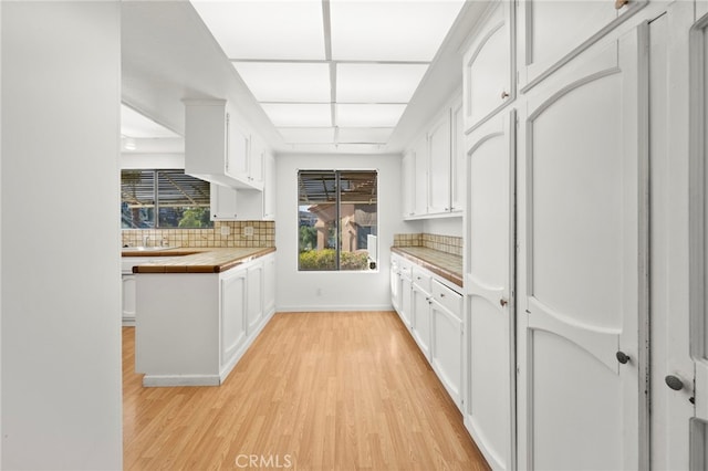 kitchen with light wood-style floors, tile counters, white cabinets, and decorative backsplash