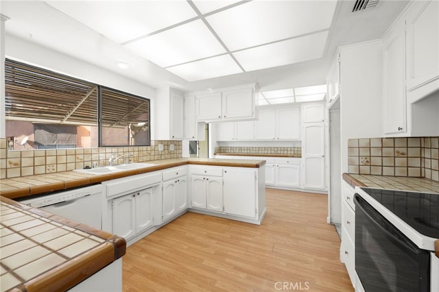 kitchen with white cabinetry, white dishwasher, a sink, light wood-type flooring, and black / electric stove