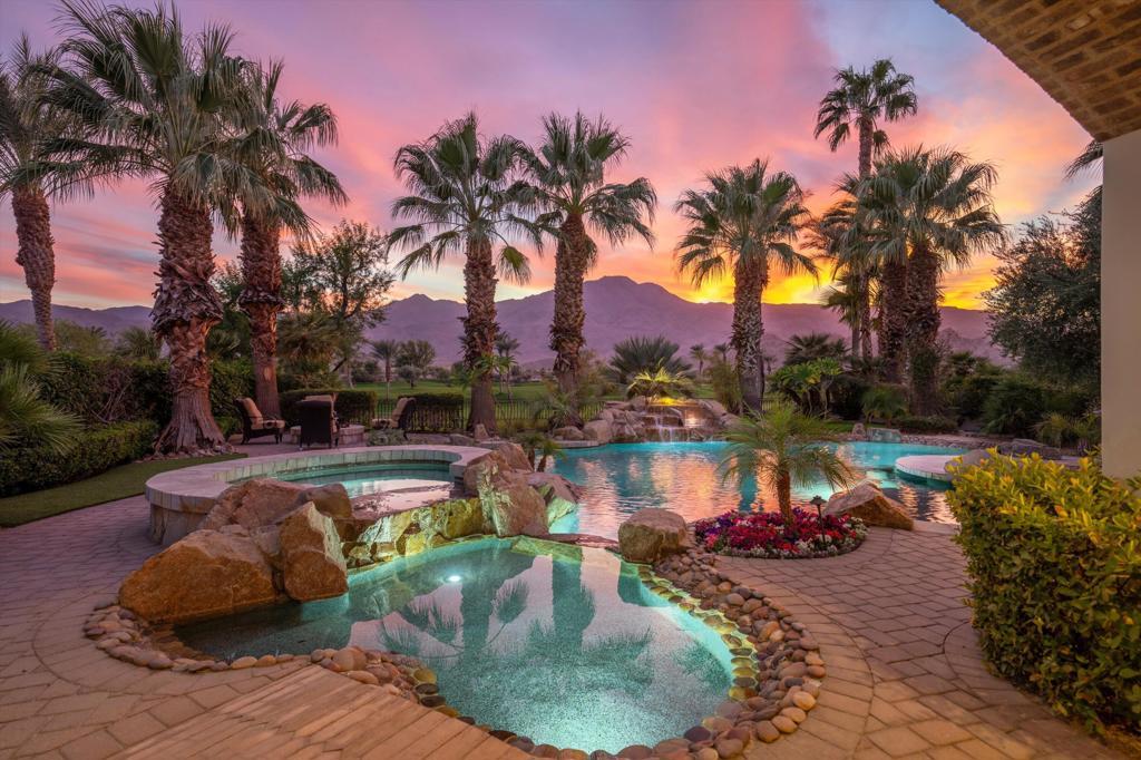 pool at dusk with a patio area, an in ground hot tub, and a mountain view