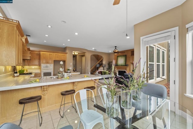 dining space featuring sink, light tile patterned floors, and ceiling fan with notable chandelier