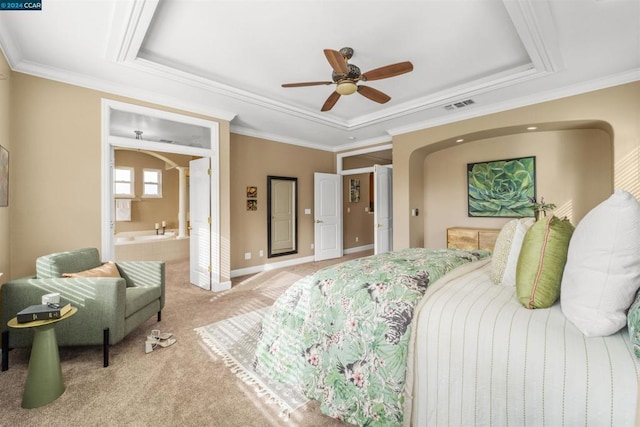 carpeted bedroom with a raised ceiling, connected bathroom, ceiling fan, and ornamental molding