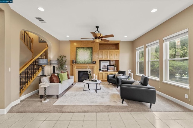 living room featuring a tile fireplace, ceiling fan, and light tile patterned floors