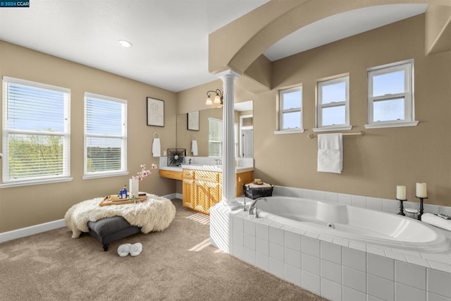 bathroom with vanity, decorative columns, and a relaxing tiled tub